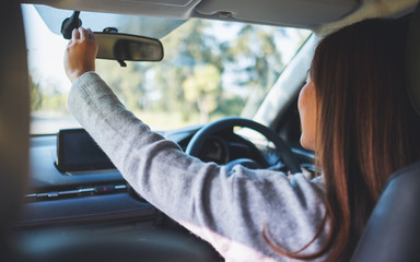 A woman adjusting a rear view mirror while driving car