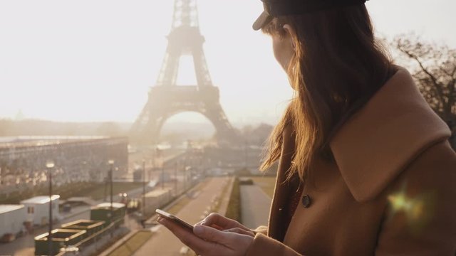 Beautiful young brunette businesswoman using smartphone shopping app at epic sunny Paris Eiffel Tower view slow motion.