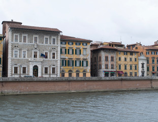 Fototapeta na wymiar Buildings along the Arno River through Pisa, Italy