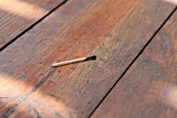 A burnt match on a wooden table. Arson concept image. 