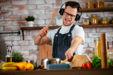 Young attractive man singing in kitchen. Handsome man in kitchen having fun.