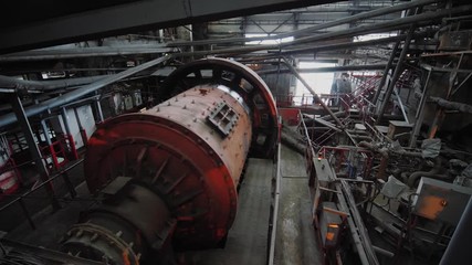 Big ball mill grinds ore on the ore-dressing factory. Industrial grinder at manufacture rotating. Copper processing industry.