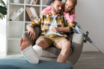 selective focus of injured and bearded man sitting near caring girlfriend