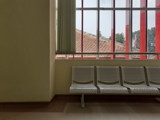 Empty White Steel Seats in Waiting Room of a Hospital with Blue Sky Windows  and Green Painted Walls Background