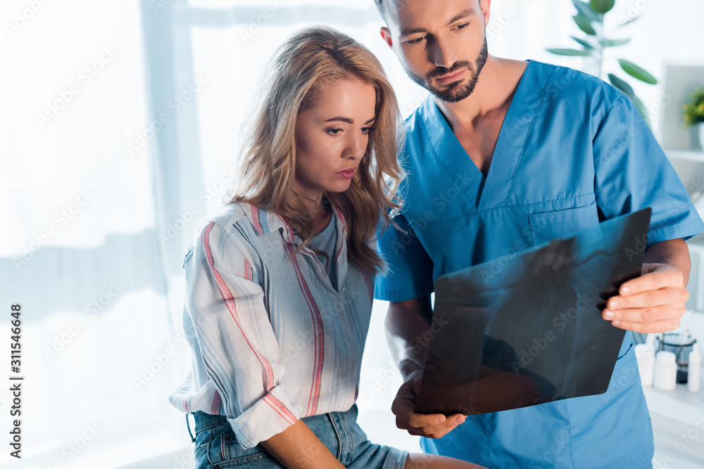 Wall mural handsome orthopedist and attractive woman looking at x-ray