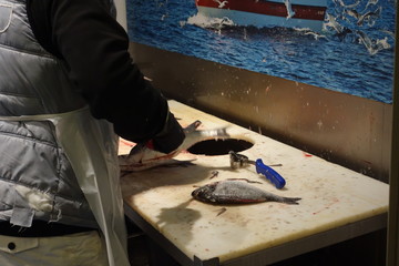 Cropped image of a back turned fishmonger cleaning the fish