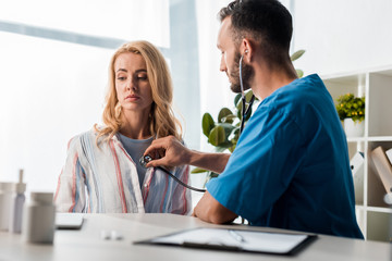 selective focus of handsome doctor examining woman