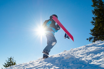 Snowboarder Climbing up with Red Snowboard in the Mountains at Sunny Day. Snowboarding and Winter...
