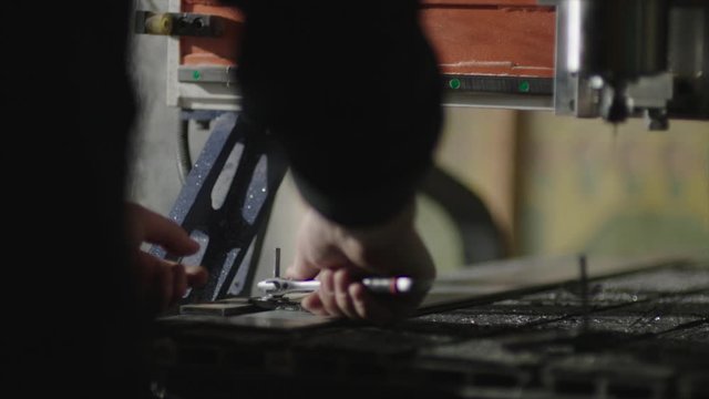 A man works at a table in a workshop. Overalls, platik, tools.