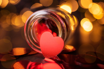 Obraz na płótnie Canvas Valentine's day concept. Small decorative jar with rhinestones in form of hearts inside and outside. Beautiful bokeh. Image is suitable for banner, poster, postcard. Lovely photo in warm colors.