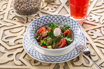 Plate of healthy green garden salad with radish, tomato and cucumber on oriental wooden table