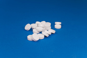 pile of white pills scattered on a blue background