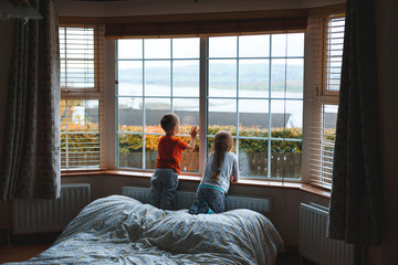 sister and brother waiting for parents at window