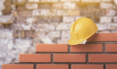 Yellow helmet with brick masonry wall with a trowel