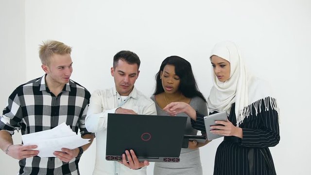 Front View Of Pleasant Young Multiracial Office Managers Which Talking With One Another While Working Together Near White Wall