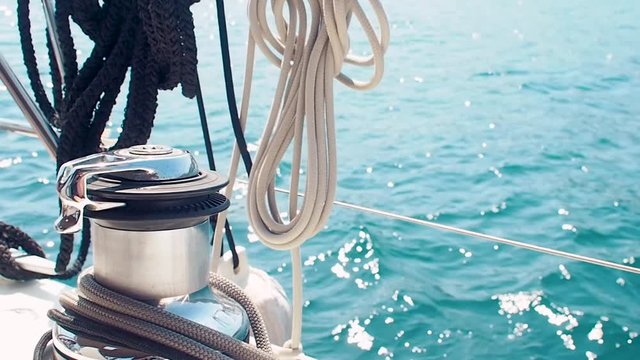 Boat trip on a yacht under sail, a fragment of the deck and a winch with a rope, the view from the deck. Sailing and yachting, rope is wound on the winch