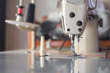 Needle of white industrial sewing machine use sew cloth close-up.
