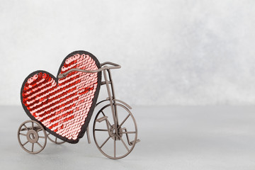 Fototapeta na wymiar toy bike carrying big red heart. Valentines day minimalism background.
