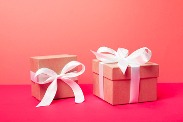 Trendy attractive minimalistic gifts on the neon pink and coral background. Merry Christmas, St. Valentine's Day, Happy Birthday and other holidays concept.