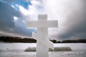 Christian cross made of ice near the ice hole in river. Holidays of Orthodox baptism. Concept of swimming in cold water. Saint Epiphany - Religious feast