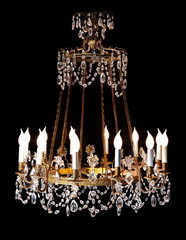 Large vintage original crystal chandelier isolated on black background.