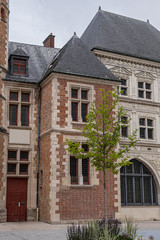 Fototapeta na wymiar Logis du Roi, a former hotel known as Trois-Cailloux, is a brick and stone building with tower housing a spiral staircase, from beginning of XVI century. Amiens, Picardy, Somme, France.
