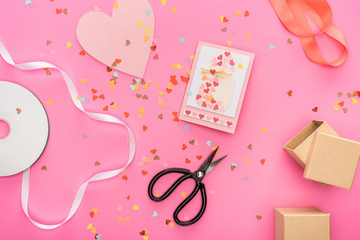 top view of valentines confetti, empty compact disk, scissors, gift boxes, greeting card on pink...