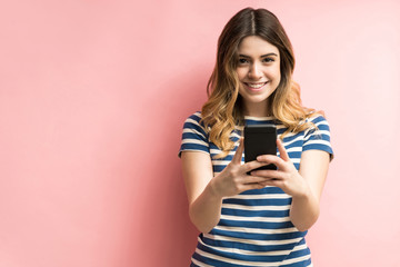 Happy Young Female With Mobile Phone In Studio