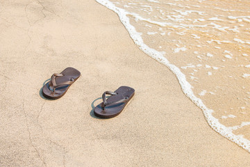 Fototapeta na wymiar Brown sandals were removed on the beach.