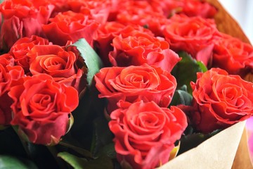 Big beautiful bouquet of red roses in craft paper with selective focus. Amazing lush lava roses for st Valentine’s Day or Mother’s Day. Greeting concept. Red roses background. Tender flowers 