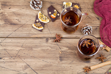 Winter hot tea with cinnamon, anise, chocolate with fruit, cone on wood brown background.