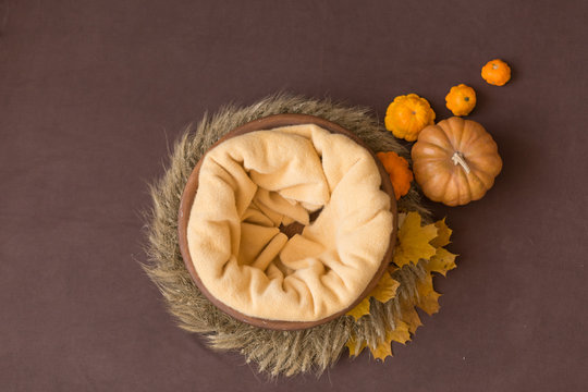 the wooden tub is decorated with autumn leaves and pumpkins. basket for newborn photo shoot. the bowl is made of solid wood. background for newborn photography