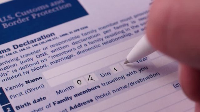 Man fills Customs Declaration Form, writes the date of birth. Close-up