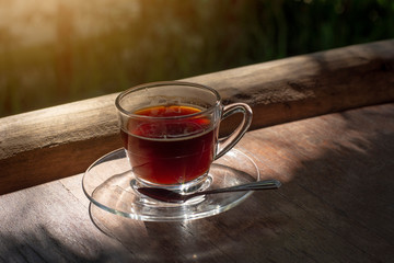 Morning coffee cup on rustic wooden table with warm morning sunlight.