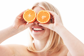 Laughing young woman without clothes with oranges cut in half at her eyes. Healthy lifestyle. Close-up. White background.