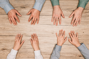 Top view of businesspeople with hands on wooden table, cropped view