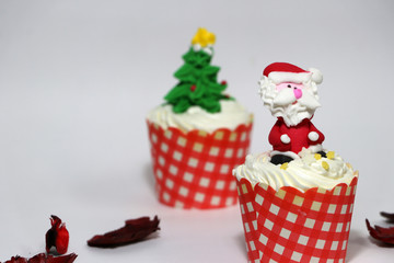 Christmas cupcakes decorated with Santa Claus and out focus Christmas tree cupcakes and colorful flower petals on the floor.