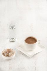 Cup of coffee served with Turkish delight on wooden table