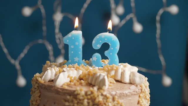 Birthday cake with 13 number candle on blue backgraund. Candles blow out. Slow motion and close-up view