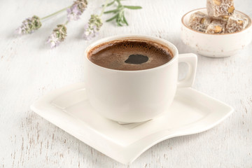 Cup of coffee served with Turkish delight on wooden table