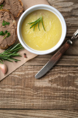 Fresh homemade chicken liver pate in ceramic bowl or ramekin and baguette slices with pate with herbs and garlic on a rustic wooden background. Top view.