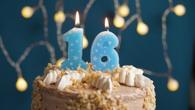 Birthday cake with 16 number candle on blue backgraund. Candles blow out. Slow motion and close-up view