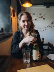 Girl drinks lemonade from glass in cosy cafe