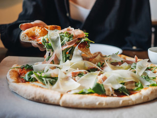 Pizza with parma ham, cheese, arugula, sauce in rustic cafe table
