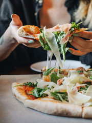 Pizza with parma ham, cheese, arugula, sauce in rustic cafe table