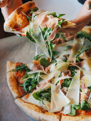 Pizza with parma ham, cheese, arugula, sauce in rustic cafe table