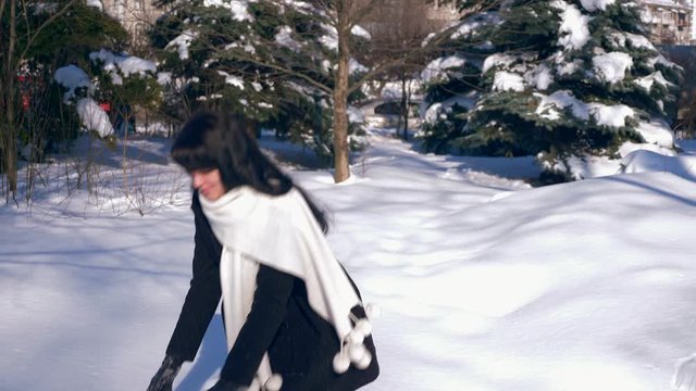 Pretty Smiling Young Adult Female Throws Snowballs. Sunny Winter Day In City Park. Slow Motion 30 fps 0.5 normal speed 60 fps
