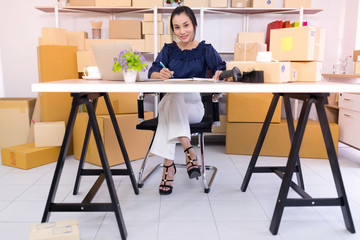 Asian women who are online shopping entrepreneurs SME are sitting at their desks and looking at the camera.