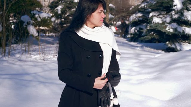 Pretty Brunette Girl Puts On Gloves On Hands. Sunny Day In Winter City Park. Slow Motion 30 fps 0.5 normal speed 60 fps