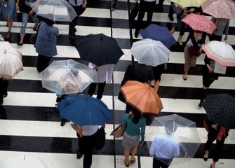 looking down on people at a crossing with umbrellas on a rainy day